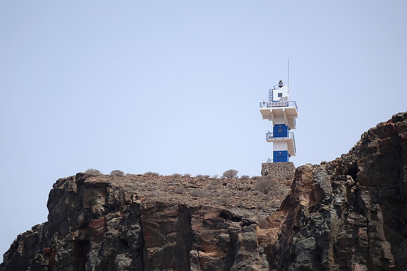 Gran Canaria / Lighthouse Punta del Castillete
square cylindrical tower with three galleries but no lantern, mounted on a 2-story square base; access to the galleries is by an external stairway that winds around the tower. The lighthouse was painted with blue and white horizontal bands in 2014. Located atop a steep hill just northwest of Puerto de Mog?n; accessible by by a stiff climb from the marina. Site open, tower closed. ARLHS CAI-006; ES-12607; Admiralty D2815.94; NGA 24023.7.
Keywords: Spain;Gran Canaria;Puerto de Mogan;Atlantic ocean